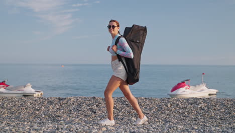 mujer con mochila en una playa cerca del océano con jet skis