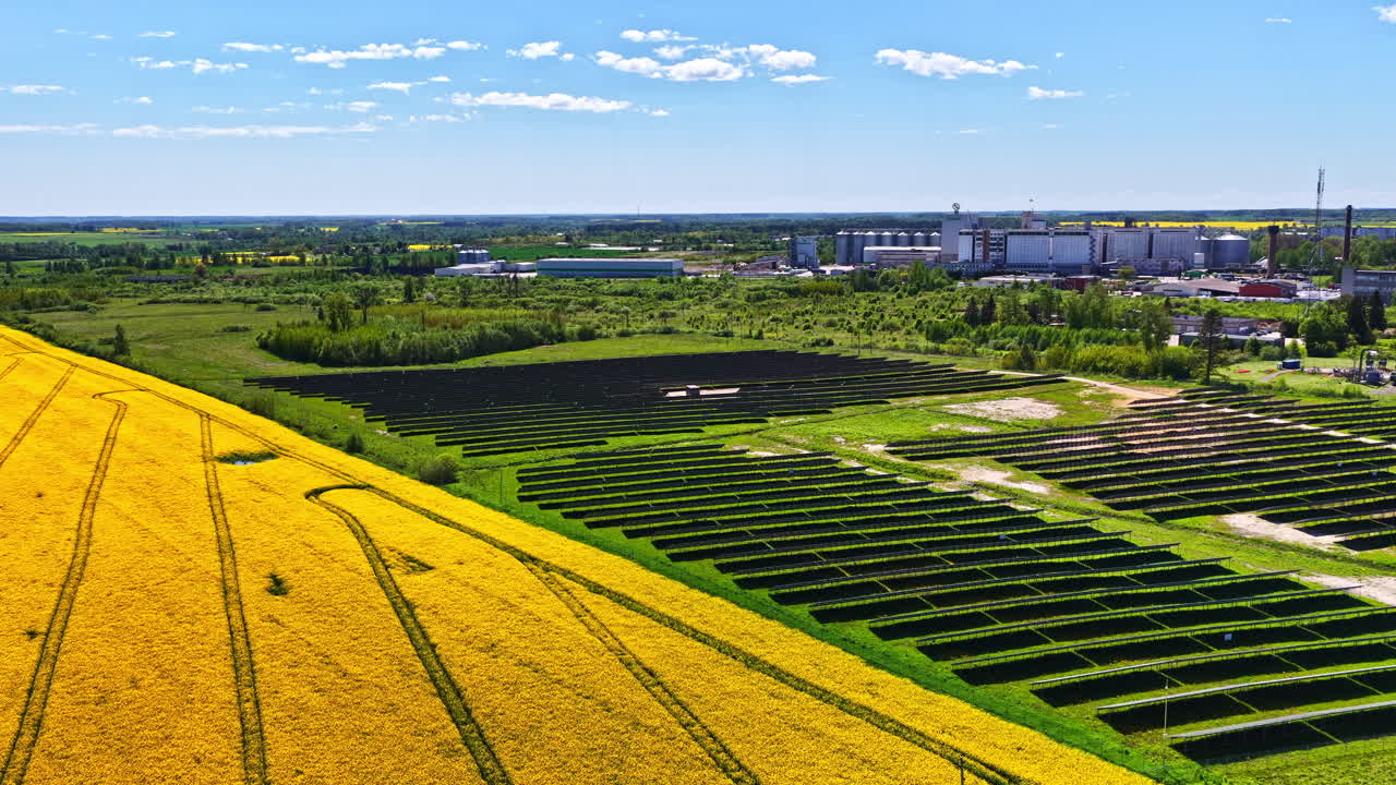 Drone shot capturing solar farm on a sunny day beside an industry. Renewable source of energy
