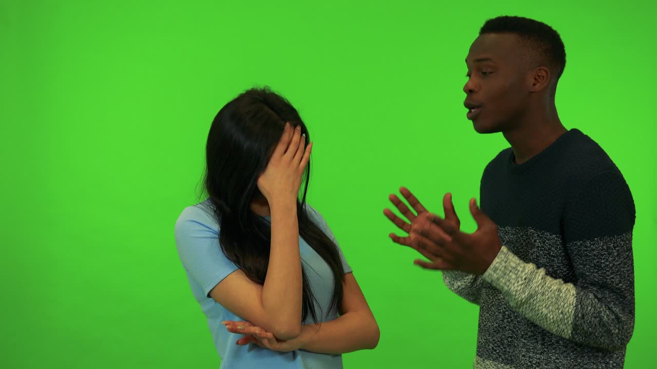 A young Asian woman and a young black man argue - green screen studio