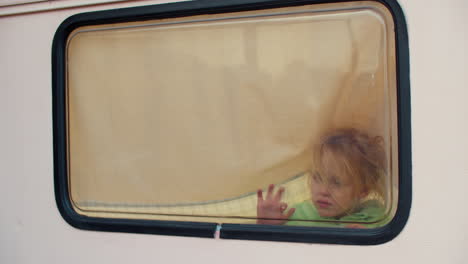 niña pequeña pinta con sus dedos en la ventana de la furgoneta