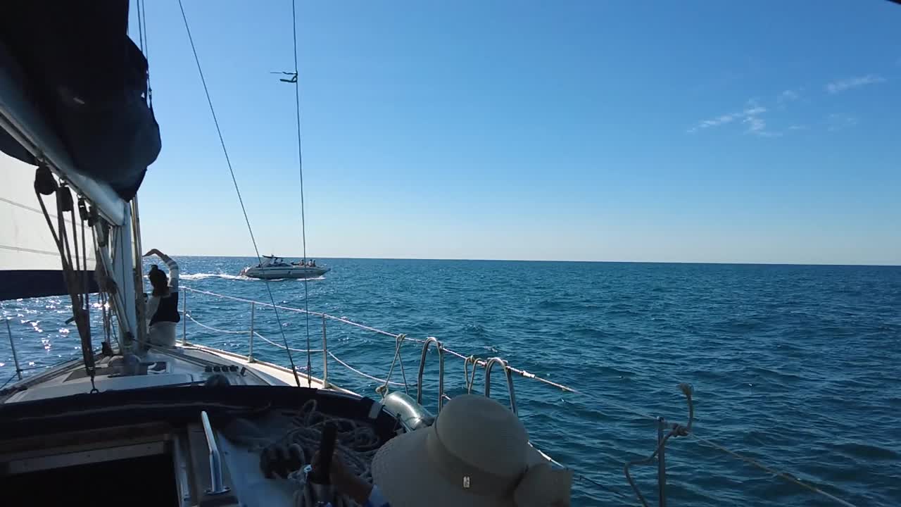 pasajero en un barco de vela saludando a otro barco, agua brillante en un día soleado