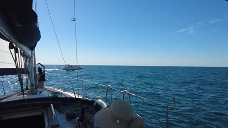 passenger in a sailboat boat waving at another boat, shiny water on a sunny day