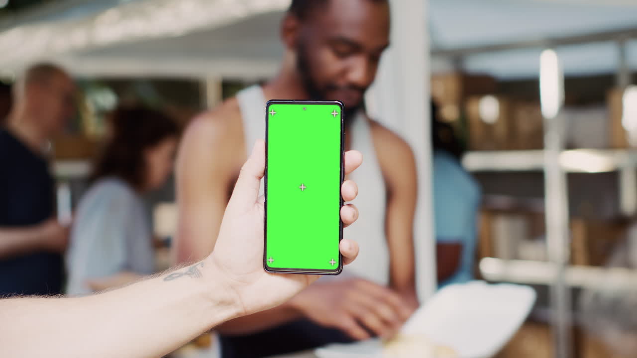persona sostiene un teléfono móvil con pantalla verde