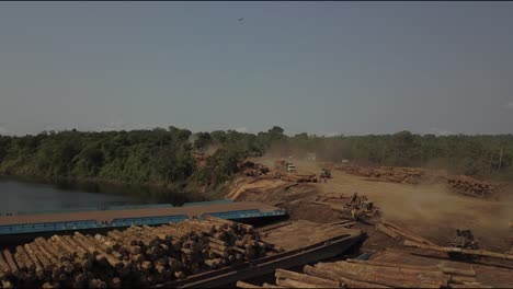 deforestation of the amazon rainforest: stacking logs on barges for transport - aerial flyover