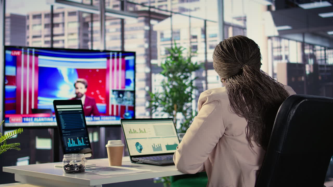 una mujer de negocios viendo una conferencia de prensa en la oficina.