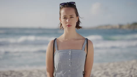 portrait of attractive young caucasian woman on beach looking confident at camera enjoying warm summer vacation day in ocean seaside background