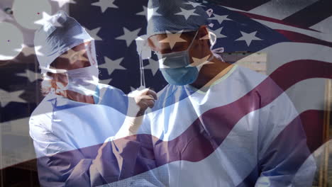 animation of flag of united states of america waving over surgeons in operating theatre