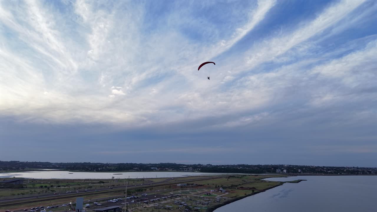Motorisert paraglider som flyr over elvelandskap ved Balneario Costa Sur under dramatiske skyer, statisk luftfoto