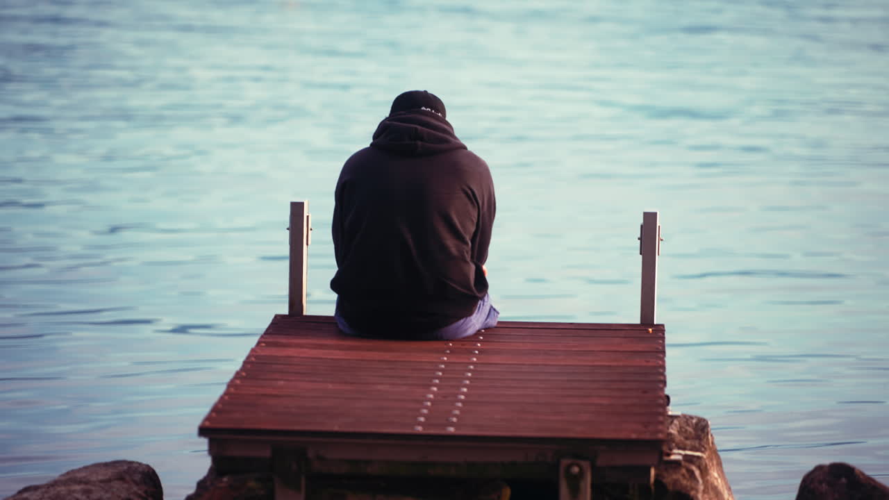 호수 에 있는 나무 플랫폼 에 앉아 있는 사람