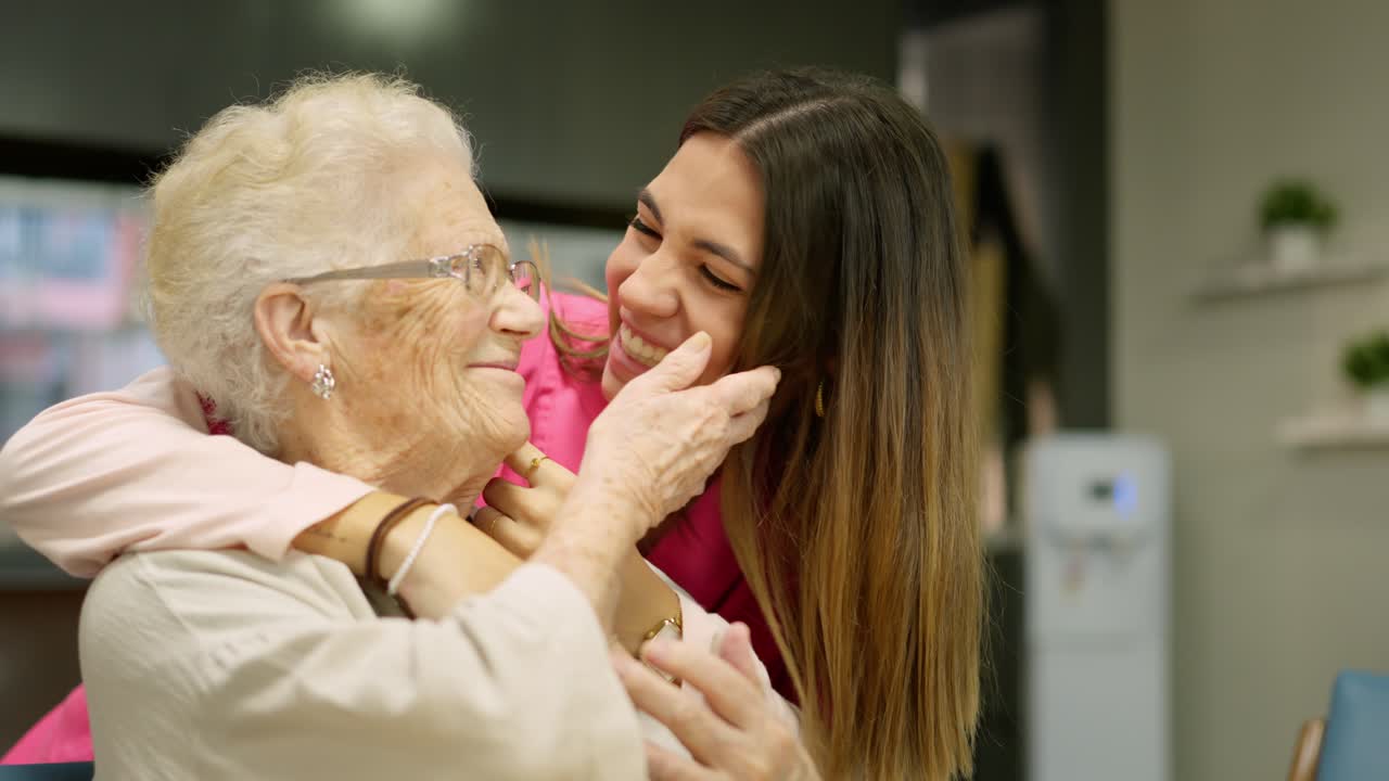 A caring young woman embraces and smiles with an elderly woman