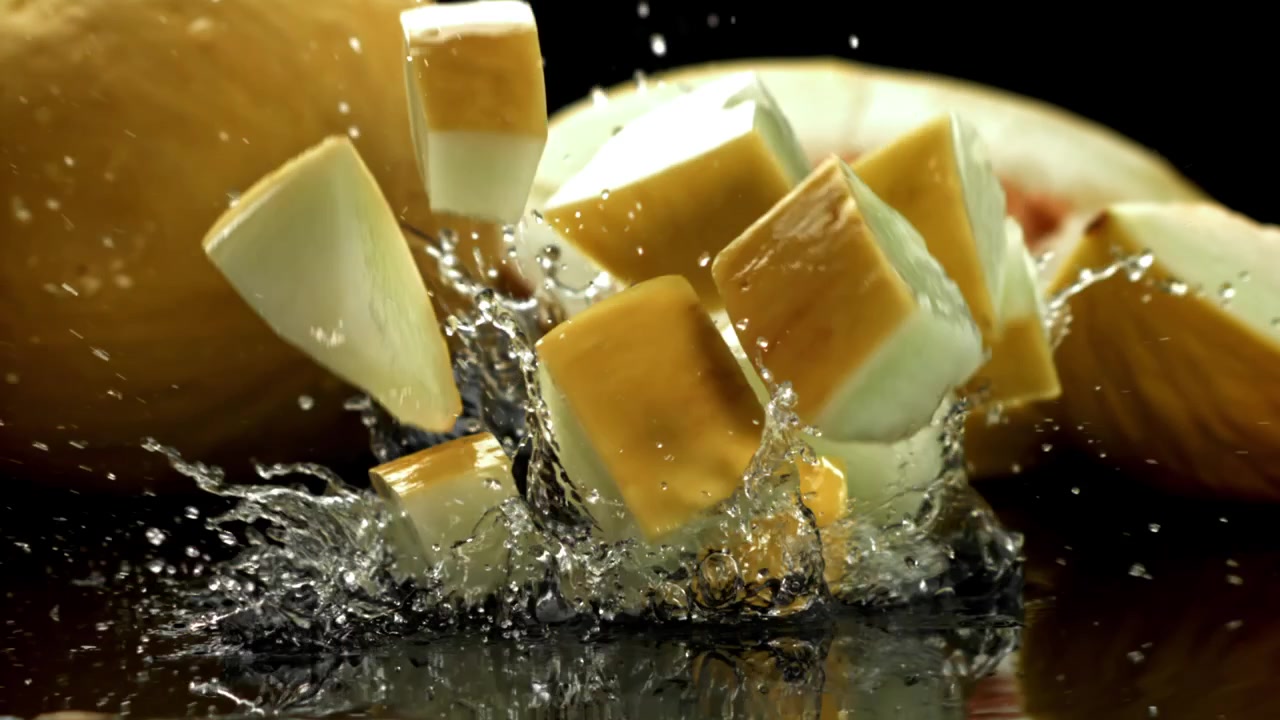 Fresh Melon Cubes and Slices Splashing into Water in Slow Motion