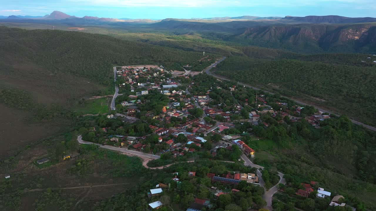 A vista aérea da Vila de São Jorge ao pôr do sol mostra o vilarejo espalhado por um planalto rico em quartzo, com casas e estradas integradas à paisagem rochosa da Chapada dos Veadeiros.