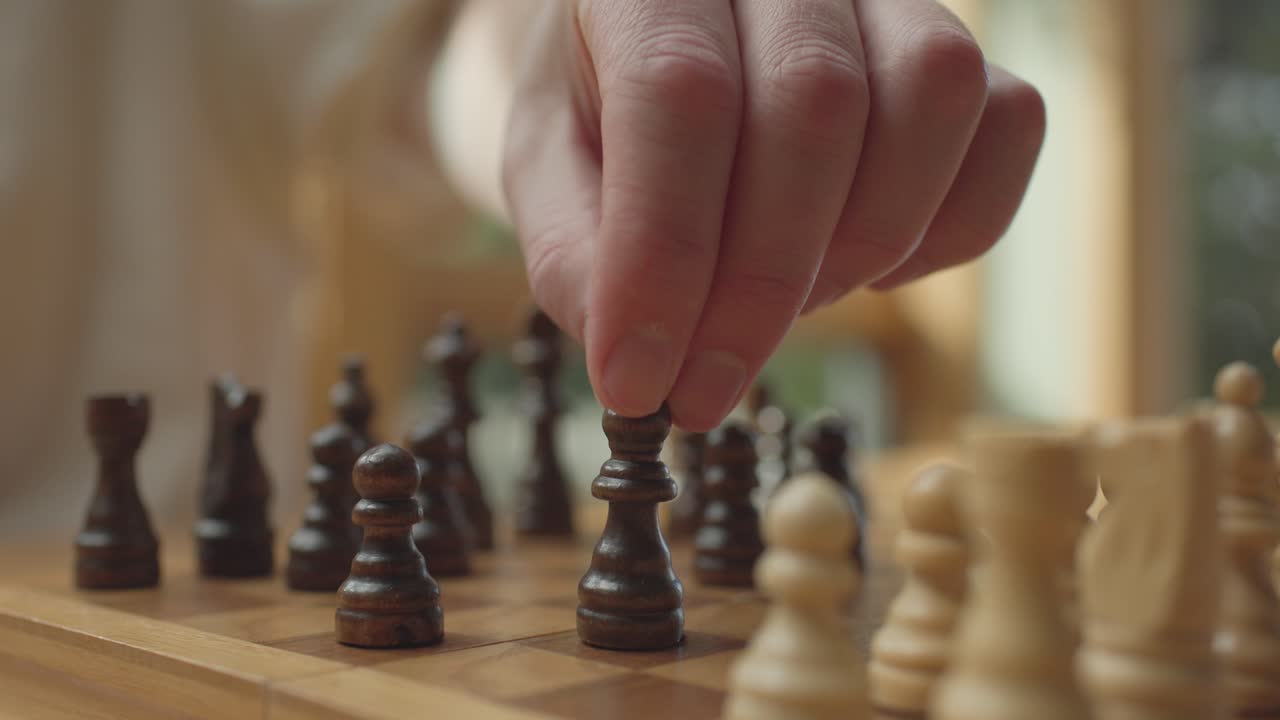 Hand moving knight on chessboard in bright, thoughtful atmosphere