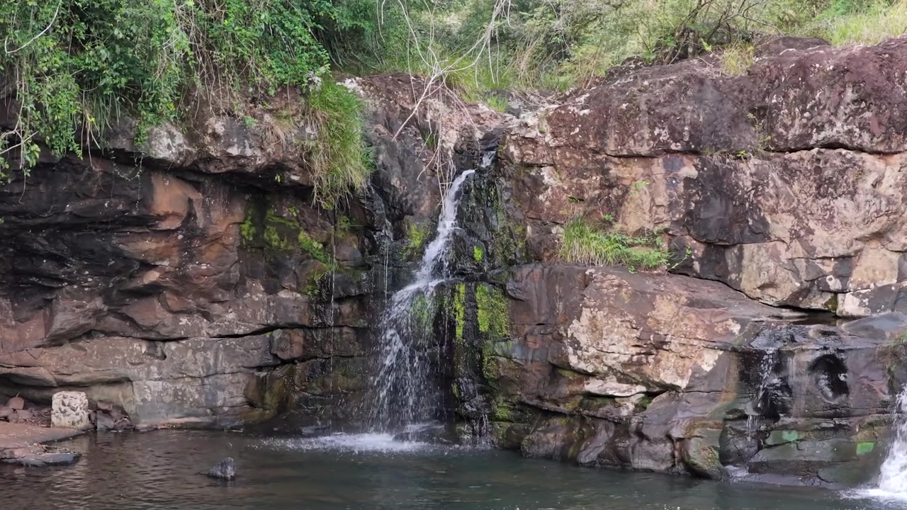 Paisagem estática de cascata de água fluindo sobre rochas em uma piscina de cachoeira.