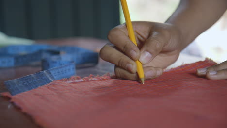 a woman's hand drawing an outline on some cloth to create an apron in oaxaca, mexico