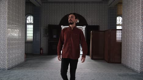 front view of a young bearded man walking through the mosque door, people visit historical and cultural places of worship