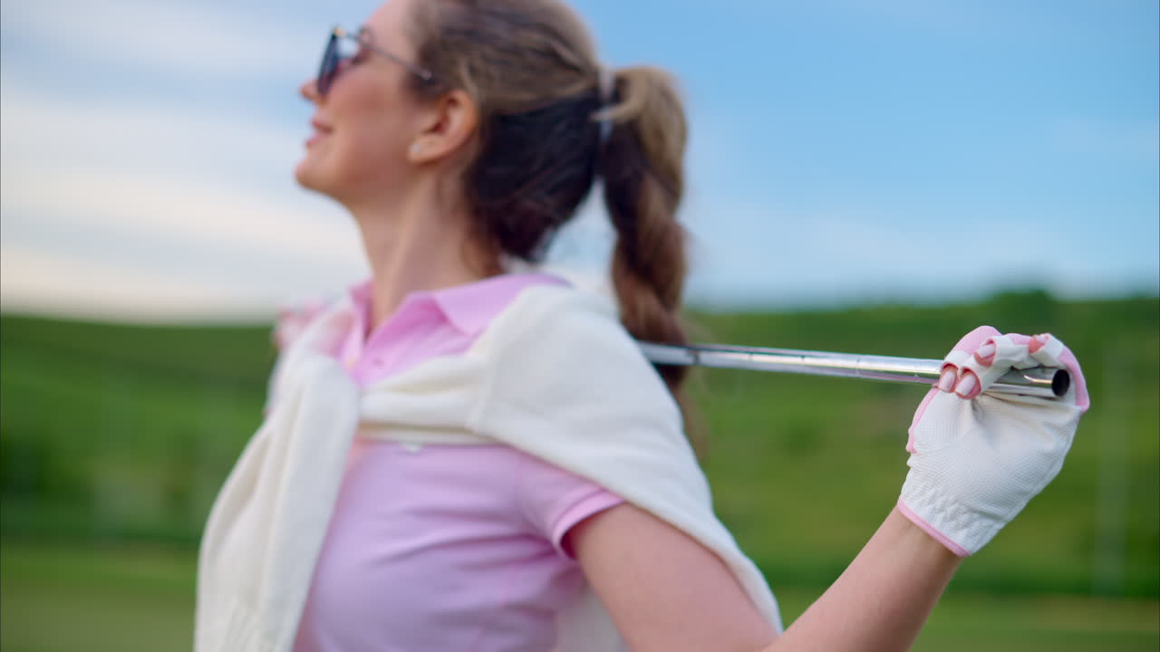 Woman holding a golf club on her shoulders, watching the sunset