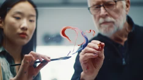 mentorship unfolds in a creative studio as a senior artist shares valuable painting techniques with a young learner. their focus highlights the exchange of skills and artistic passion.