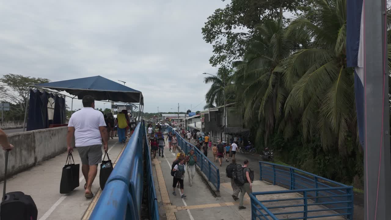 Travelers Walking on a Pedestrian Bridge at a Tropical Border Crossing