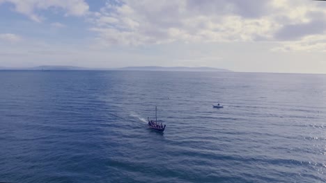 aerial shot of viking ship sailing on the ocean coming towards camera