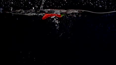 pimienta dulce roja vibrante que se deja caer en el agua en cámara lenta
