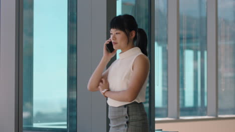 asian business woman using smartphone corporate sales executive chatting to client financial advisor negotiating deal sharing expert advice having phone call in office looking out window