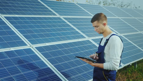 Der-Ingenieur-Verwendet-Das-Tablet-Vor-Dem-Hintergrund-Von-Sonnenkollektoren-Alternativer-Energie-Und-Sonnenenergie