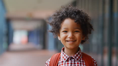 Portrait-Of-Smiling-Male-Elementary-School-Pupil-Outdoors-With-Backpack-At-School