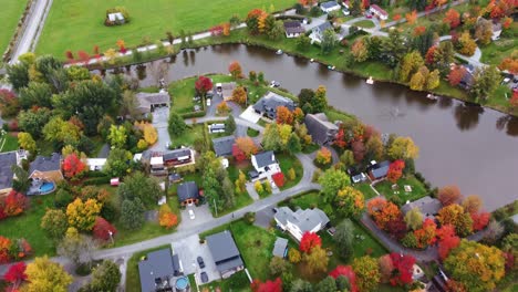 Genießen-Sie-Atemberaubende-Luftaufnahmen,-Während-Eine-Drohne-An-Einem-Sonnigen-Herbsttag-über-Ein-Bezauberndes-Viertel-An-Einem-Ruhigen-See-Fliegt