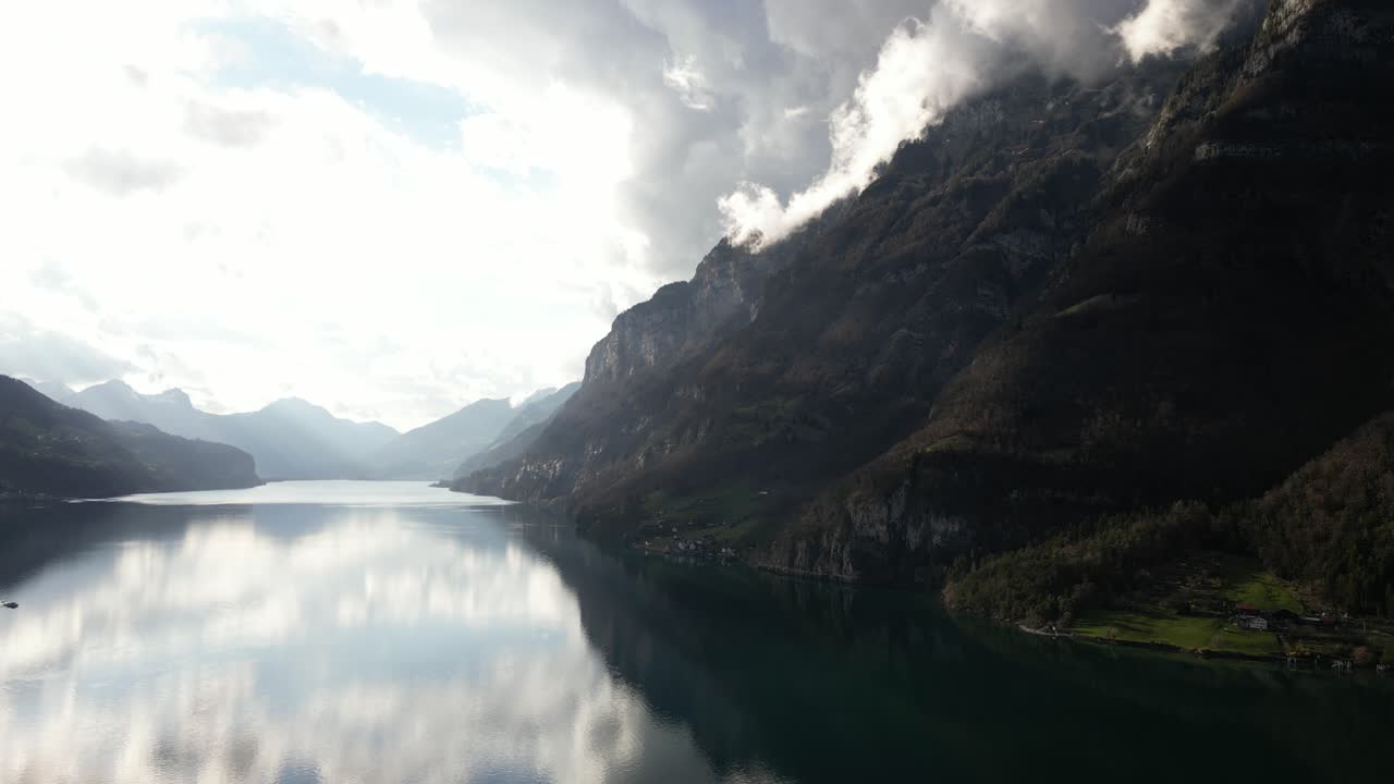 las aguas serenas y tranquilas de walensee, cerca de walenstad en suiza, están acompañadas de montañas veladas en nubes, aumentando su atractivo