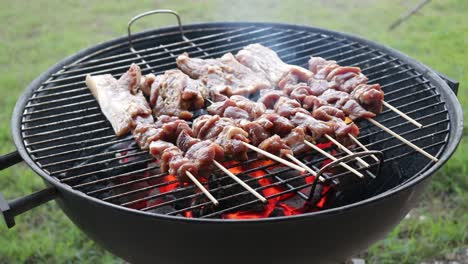 meat on a charcoal bbq while arranging burning charcoal