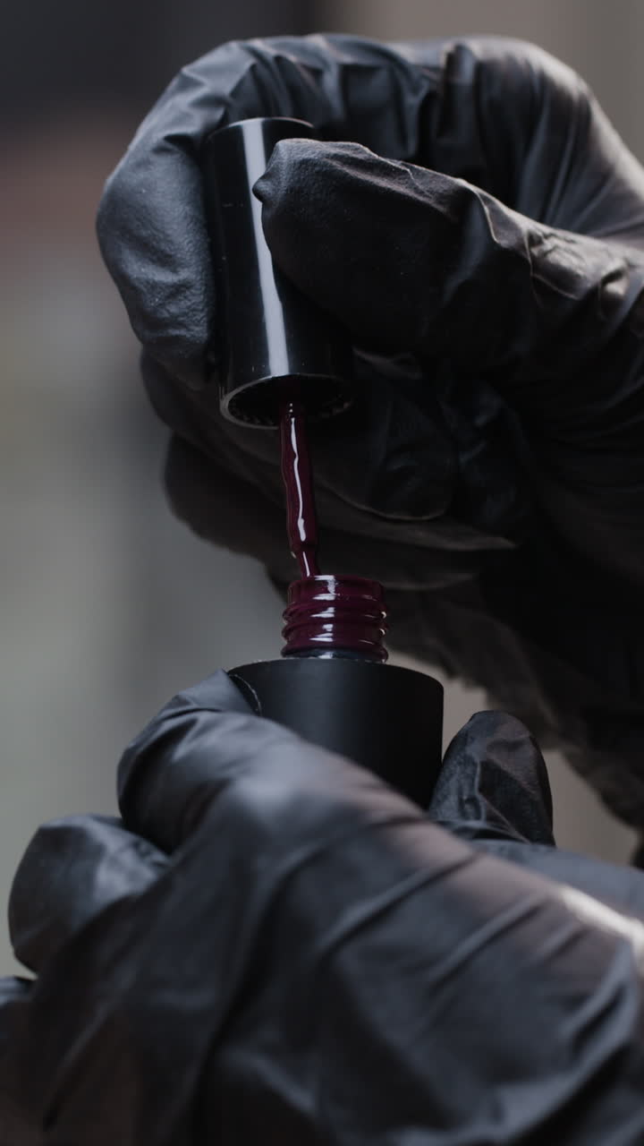 Applying Reddish-Purple Nail Polish with Black Gloves
