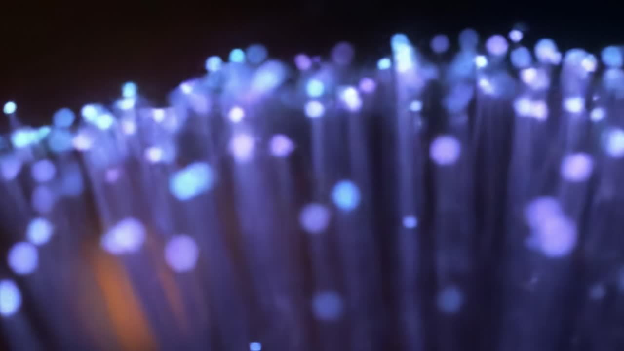 Bright, colorful lights pulse and shift in a mesmerizing pattern during an outdoor evening event. The atmosphere is lively with spectators enjoying the captivating show.