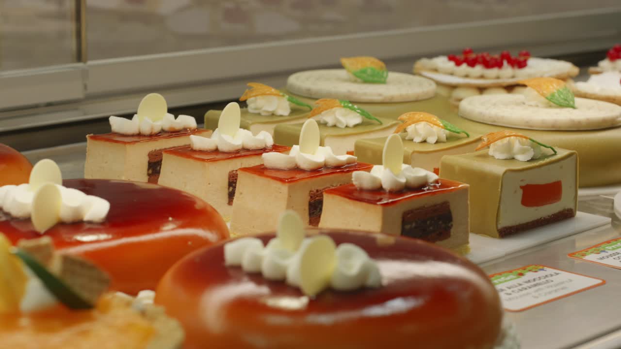 Wide selection of gourmet cakes displayed neatly in a pastry shop showcase.