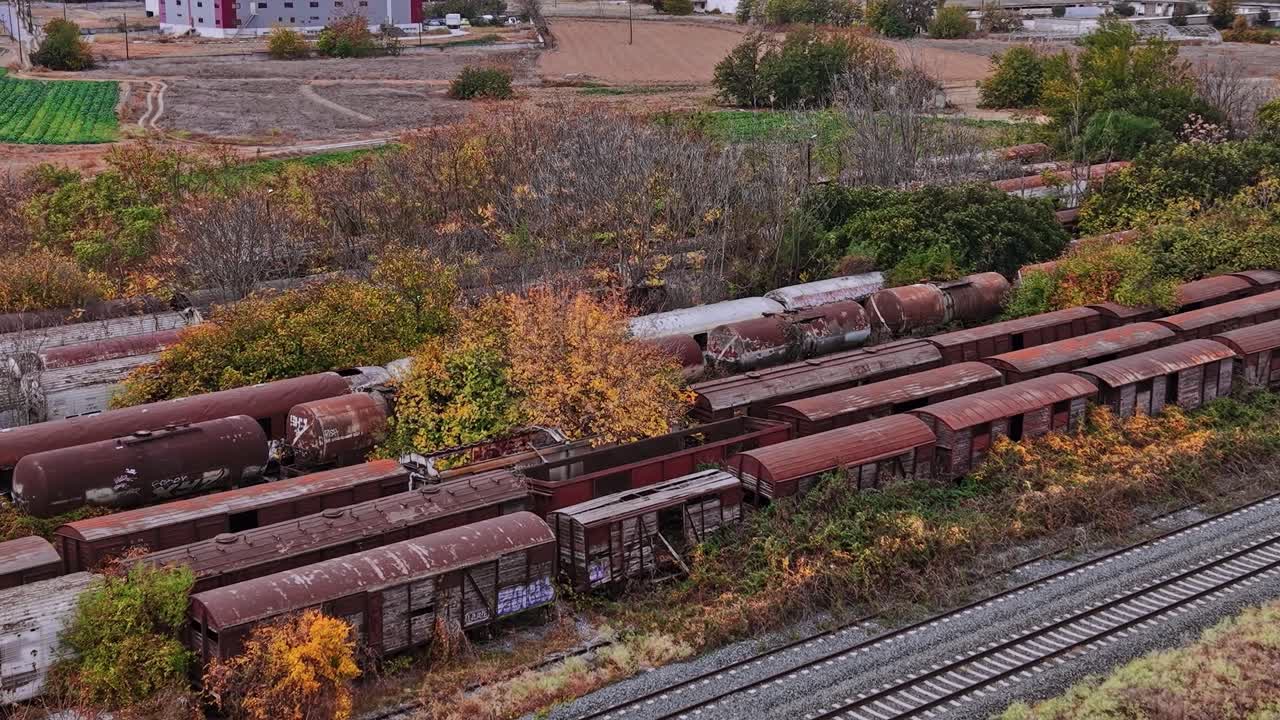 Vagones de tren en un campo cerca de edificios abandonados en Grecia durante el otoño