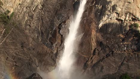 a rainbow forms near the bottom of a cascading waterfall