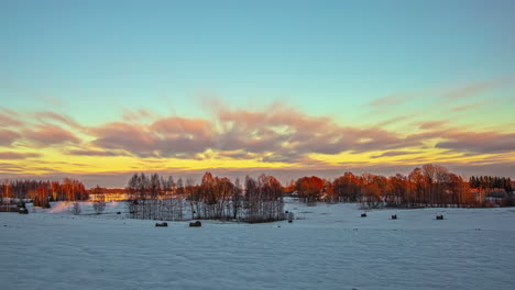 timelapse d'un ciel jaune virant au rose sur un paysage enneigé avec des arbres en arrière-plan