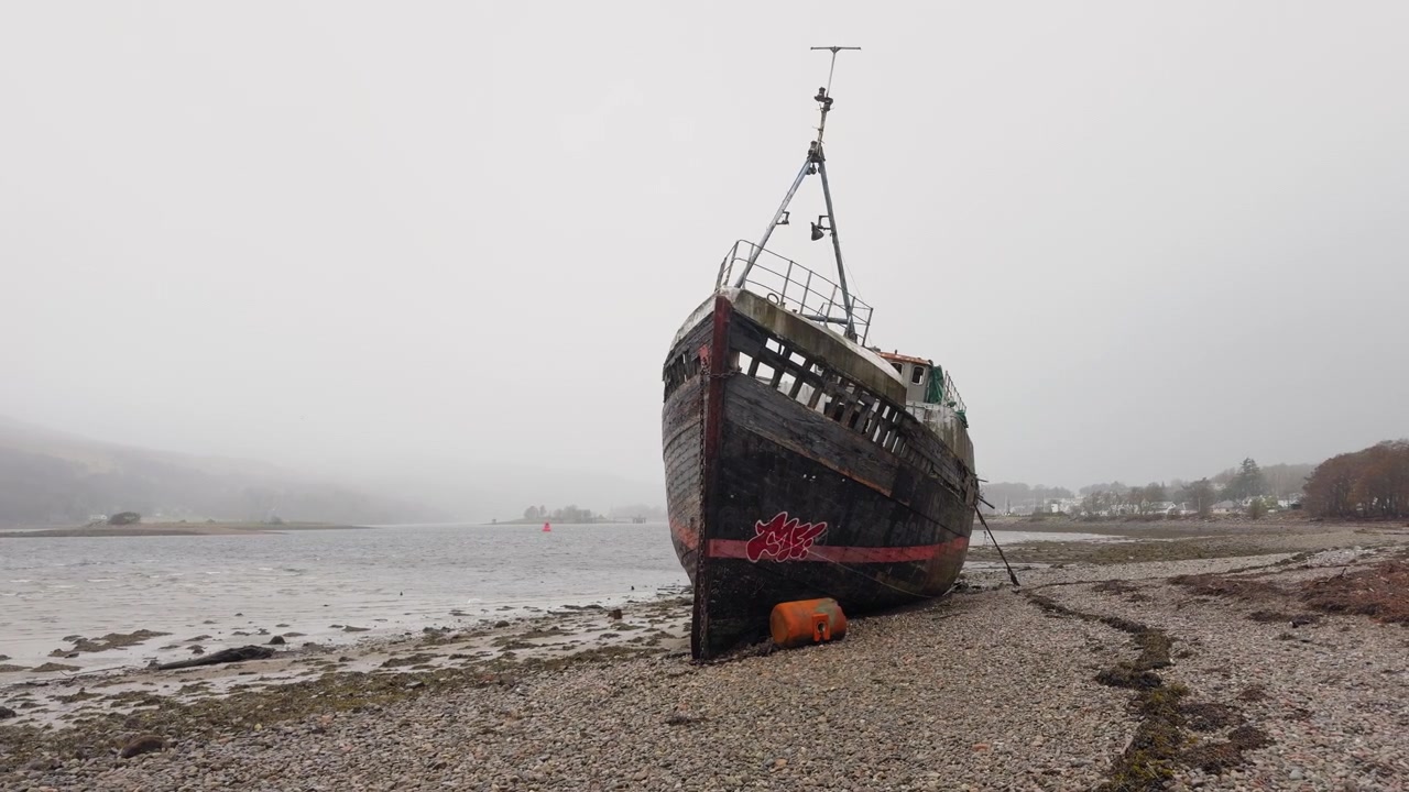 Langsom panorering med kamera af Corpach-vraget, Loch Linnhe, Skotske Højland, overskyet dag, forfaldent rustent fartøj, Skotland.