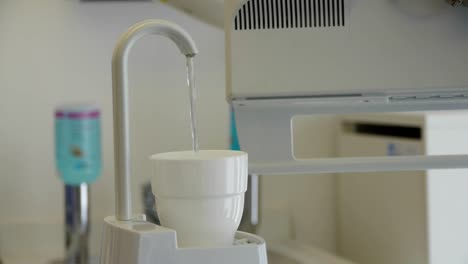 Una-Taza-Para-Enjuagar-Se-Llena-Automáticamente-Con-Agua,-En-El-Dentista