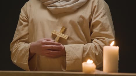 close up shot of man wearing robes representing figure of jesus christ holding wooden cross