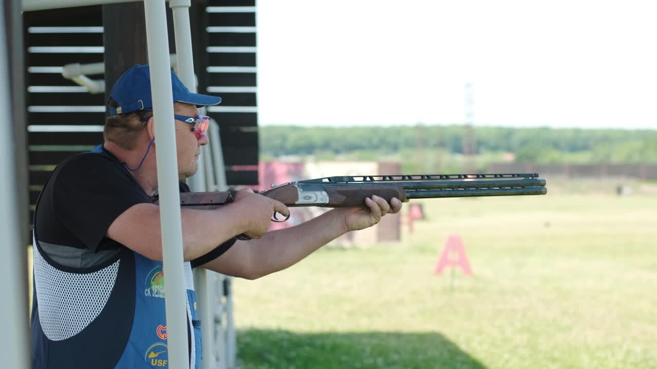 un deportista dispara con una escopeta de doble cañón, un campo deportivo para una prueba de tiro está disparando a un esquete volador