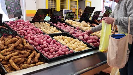 person choosing potatoes at a market stall