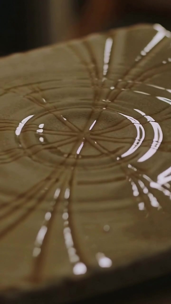 Vertical video: Rippling textured plate showing waves from central hit in kitchen with liquid gleam
