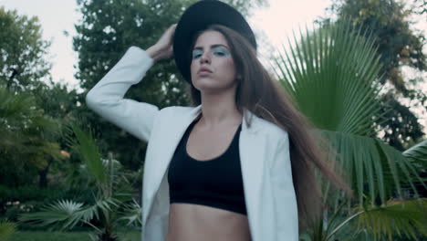 young girl model walking through tropical garden and looking at camera