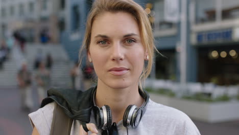 portrait of independent blonde woman looking serious staring intense wearing headphones on urban city background