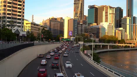 Rush-hour-inbound-and-outbound-vehicle-traffics-on-M3-Pacific-Motorway-with-riverside-downtown-cityscape-in-the-background-at-sunset-golden-hours