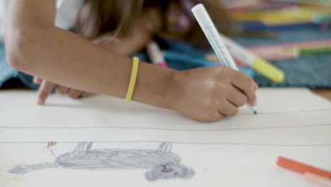 Close-Up-Shot-Of-An-Unrecognizable-Girl-Lying-On-Floor-And-Drawing-Line-With-Felt-Pen-On-Paper