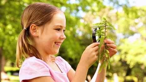 Little-girl-looking-at-plant-through-magnifying-glass