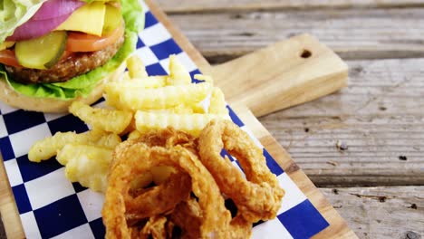 Hamburger,-onion-ring-and-french-fries-on-chopping-board