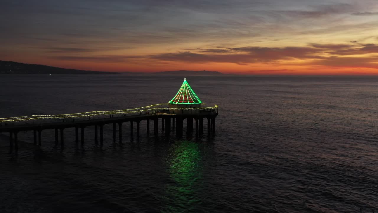 Green Christmas Lights Decorated Over Manhattan Beach Pier During Dusk In California, United States. Aerial Pullback Shot